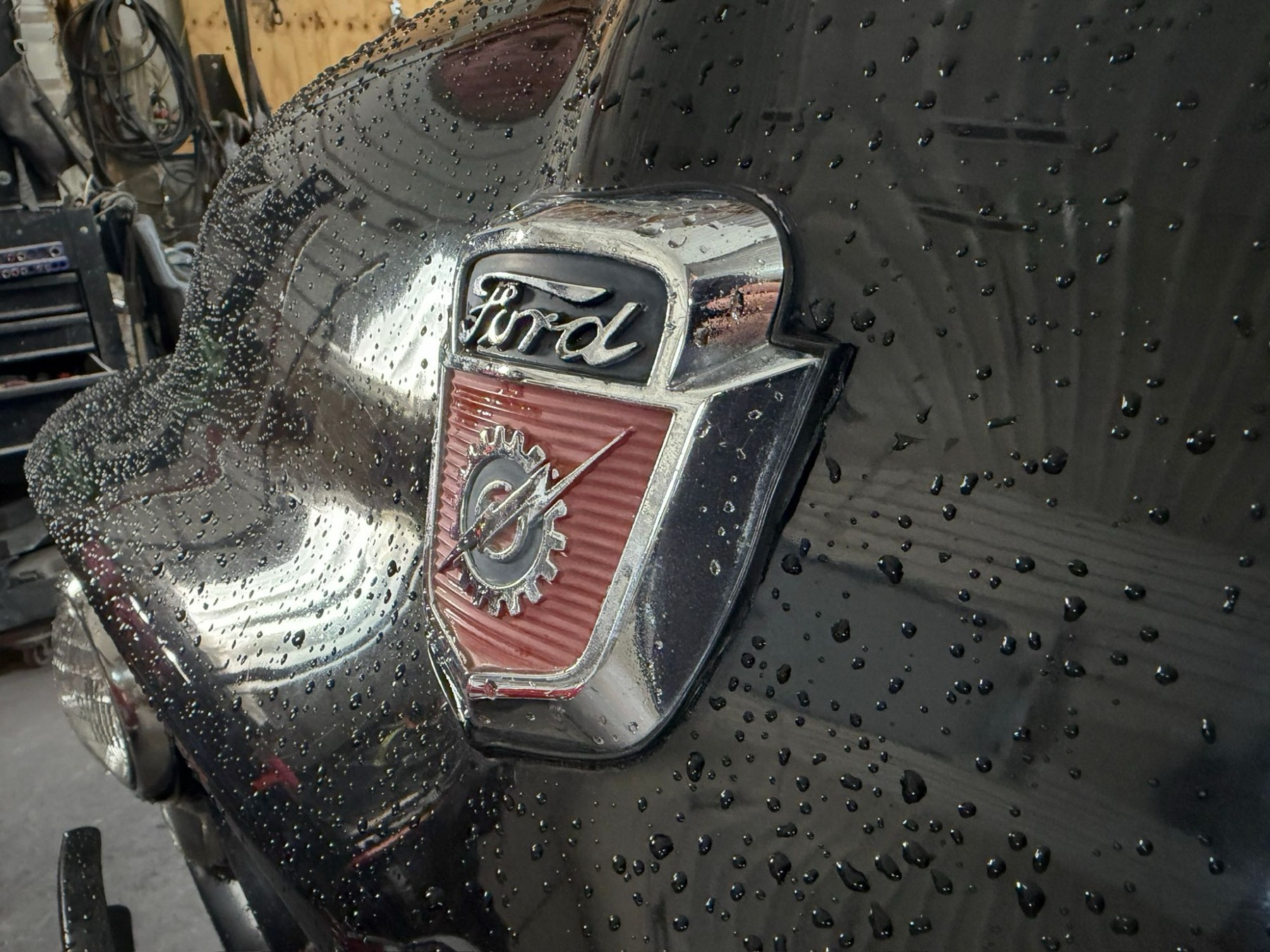 Close-up of a chrome Ford shield emblem on black paint